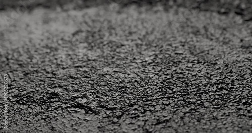 Macro Cracked Mud Texture on Black. Slow panning footage across a fissured dark surface, showcasing intricate polygonal crack patterns and rough granular details under subtle directional lighting.