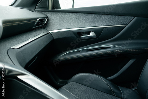 Interior details. Modern black car interior, leather steering wheel, climate control, large navigation system screen.