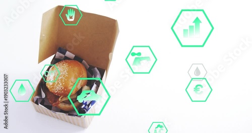 Sesame burger sitting in box, green hex icons emerging right, drifting showing eco metrics