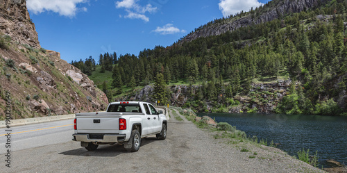 Foto Pickup truck on the beautiful road along the mountain river and forest