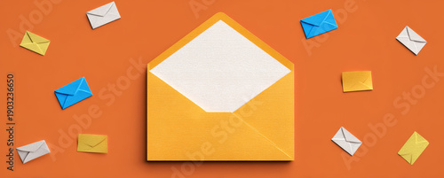 Open yellow envelope with white paper inside surrounded by miniature colorful paper envelopes on orange background