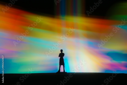 Fotografía Silhouette of a person standing beneath a vibrant abstract light installation