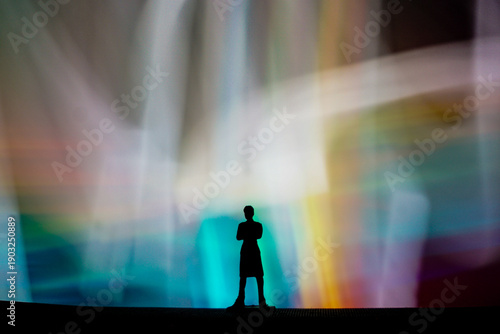 Fotografija Silhouette of a person standing before a vibrant light spectacle