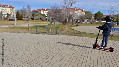 Young boy riding an electric scooter in a public park