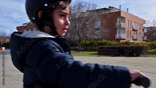 Young boy with helmet riding electric scooter in the park
