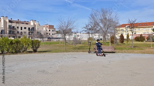 Child riding an electric scooter in an urban park on a sunny day