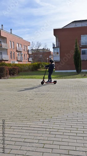 Young boy with a helmet riding an electric scooter in a park