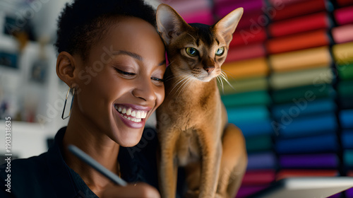 Black woman illustrator smiling while drawing with cat perched on shoulder