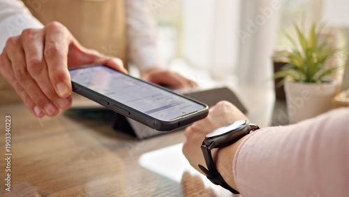 A person uses a smartwatch for contactless payment on a smartphone in a modern office. The scene highlights digital transactions, online shopping, and modern banking solutions.