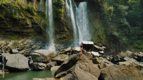 Wallpaper Mural Slender woman walking on rocks with waterfalls surrounded by lush green cliffs. Torontodigital.ca