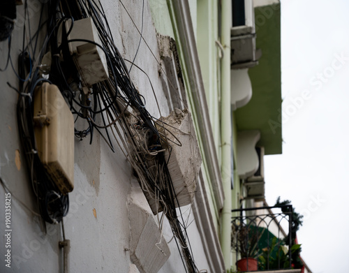 Detached facade decoration hanging on overhead wires above pedestrians.