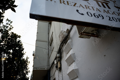 Detached facade decoration hanging on overhead wires above pedestrians.