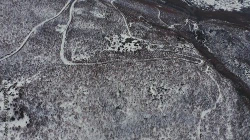 Aerial view of a snowy winding mountain road in winter
