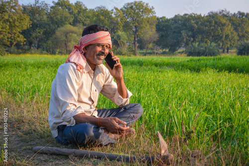 Indian farmer talking on mobile phone in green field. Digital connectivity in rural farming life