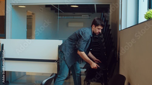 Man walks through modern office space in daylight while people work at desks in the background