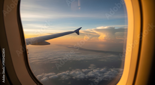 Airplane window view Passenger view of airplane wing with sunset colors and cloud formations