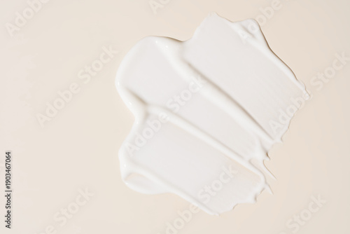 Texture of white cream on blue background. Smear of moisturizer close up. Lotion swatch. Beauty skin care product smear smudge. SPF sunscreen cream sample on beige background