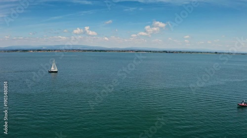 Aerial view Torreira Portugal sailboat red motorboat on calm lagoon water scenic horizon with distant shoreline blue sky clouds peaceful maritime travel summer destination traveling coastline greenery