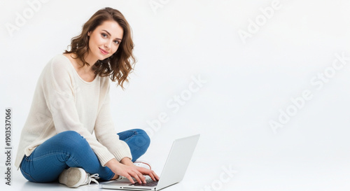 Casual young woman works on her computer on a white background. Smiling female student working or learning online with laptop. Happy girl in casual clothes using a portable computer. Work from home . 