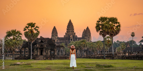Foto Woman in White Dress Walking Toward Angkor Wat Temple at Sunset, Cambodia