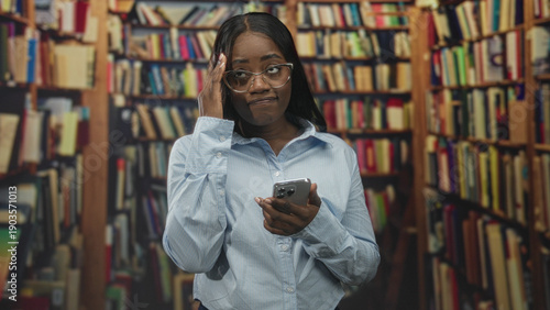 Foto Woman holding smartphone, hand on forehead reading a message in a building library; concern study focus