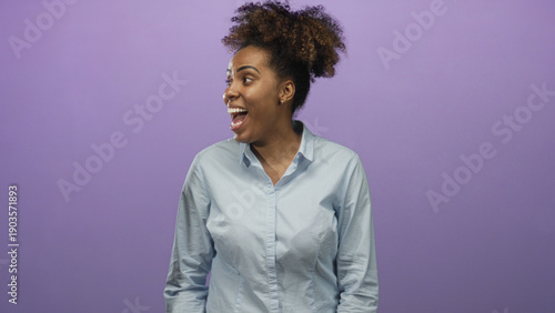 Billede på lærred Woman laughing with open mouth and visible face, turning head to the left and gesturing with one hand in purple studio; joy optimism