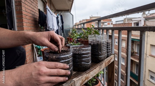 A close-up shot of hands planting small seeds into repurposed plastic bottle containers filled with soil on an apartment balcony, emphasizing sustaina