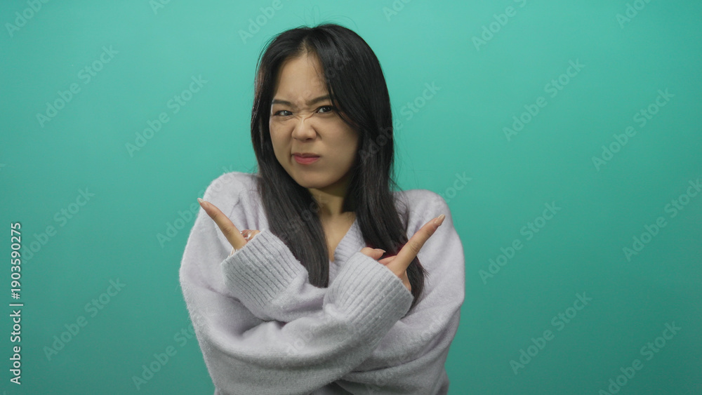 Fototapeta premium Woman pointing with hands in different directions against an isolated green background wall, expressing indecision or confusion.