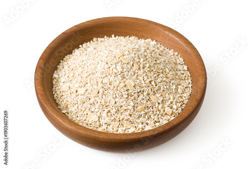 Uncooked oat bran in the wooden plate, isolated on white background.
