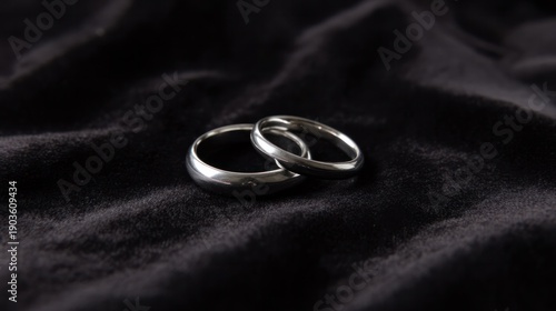 Paired silver wedding bands resting on black velvet fabric with soft luminous highlights. lifestyle magazines, social media lookbooks, designed for lifestyle magazines and social media content.