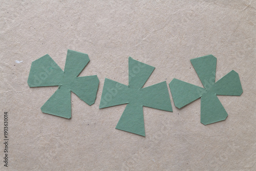 abstract cut green paper cruciform shapes on brown