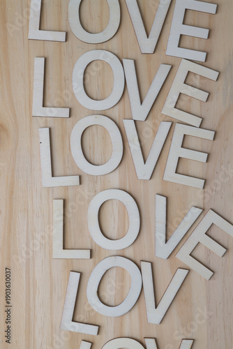 the word love composed with wooden letters repeated on a pine surface