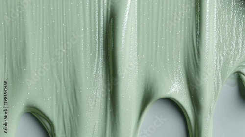 Glowing green paint slowly drips down surface creating artistic texture patterns