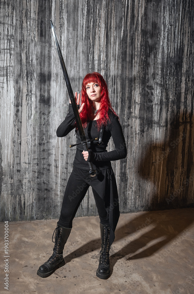 Naklejka premium Dark fantasy beautiful redhaired woman with sword against grunge wall