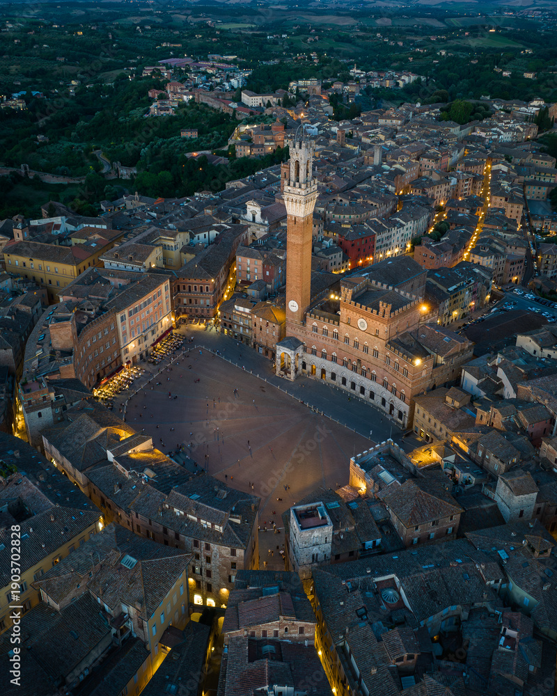 Fototapeta premium Aerial view of Piazza del Campo in Siena with city lights glowing around the medieval square. Iconic historic landmark in Tuscany, Italy, known for its unique shell shape and cultural heritage