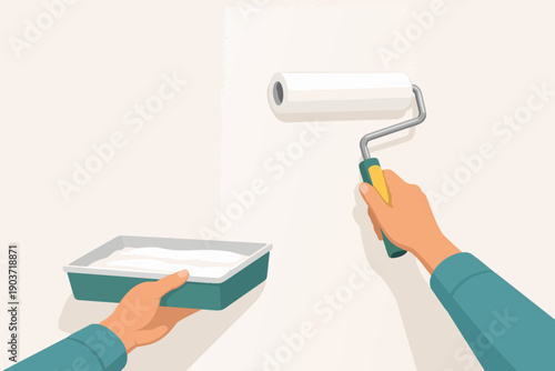 Hands holding paint roller and tray, renovating room wall with white coating