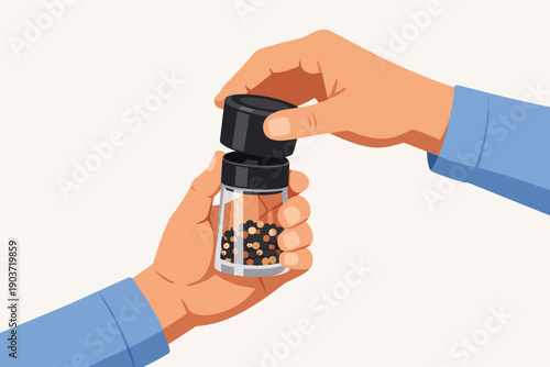 Hands grinding a pepper mill with black peppercorns for seasoning food