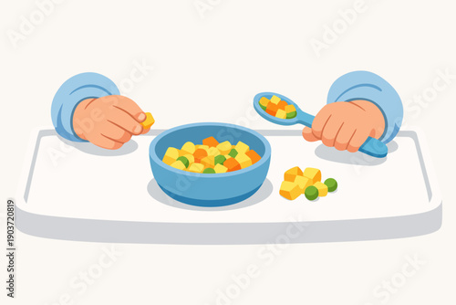 Baby learning to eat solid food using hands and a spoon in high chair