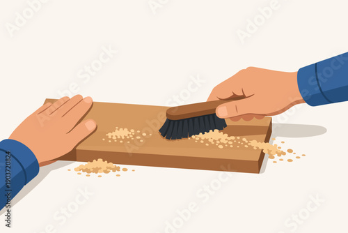 Worker hands brushing sawdust from a wooden plank after woodworking activity