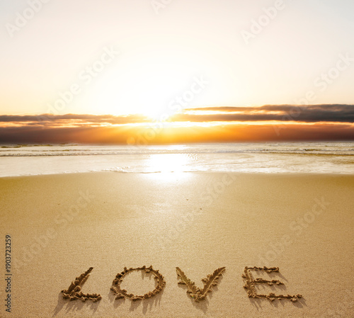 Sonnenuntergang am Meer mit dem wort LOVE in den Sand geschrieben