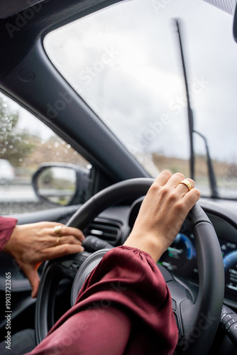 A woman is driving a car with her hands on the steering wheel