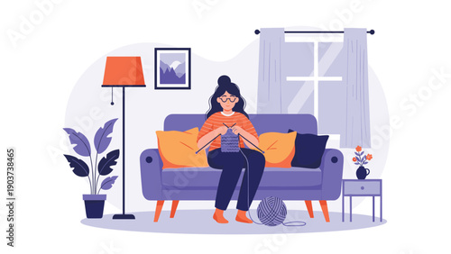 Young woman wearing glasses sitting on a cozy purple sofa and knitting a blue scarf in her living room during a quiet evening at home.