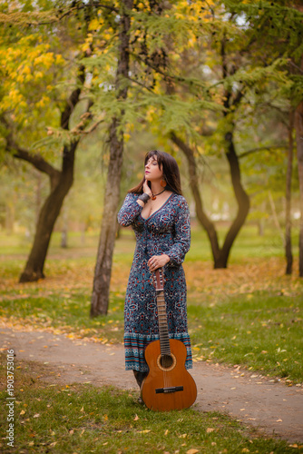 Reflections during a walk in the park: a woman with an acoustic guitar under a tree, a musician in autumn