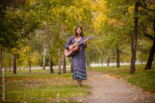 Reflections during a walk in the park: a woman with an acoustic guitar under a tree, a musician in autumn