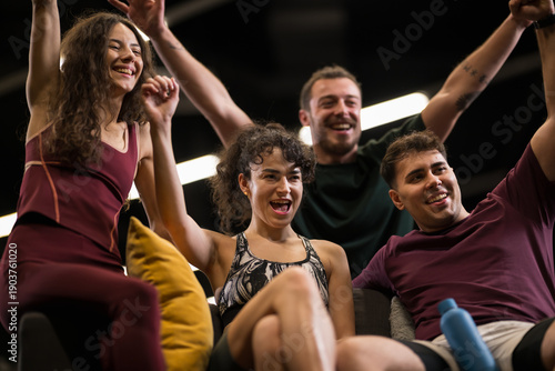 Εκτύπωση καμβά Group of friends celebrating after a fitness class in a gym with bright lights a