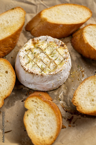 oven-fried round soft white cheese in a mold with pieces of crispy baguette with spices, delicious cheese with mold and wheat flour baguette with natural spices