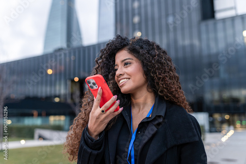 Young business woman using a mobile phone, engaging with technology, and communicating in an urban city environment