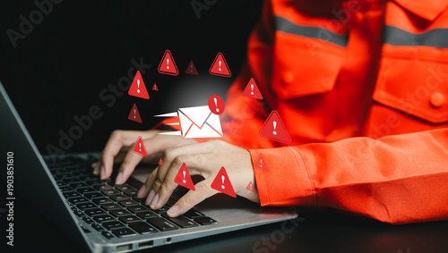Cyber risk alert concept. Industrial worker typing on laptop with email warning icons, phishing detection, cyber threat awareness, digital security incident response