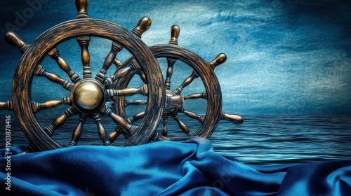 Two antique wooden ship wheels resting on blue satin fabric with a textured ocean background