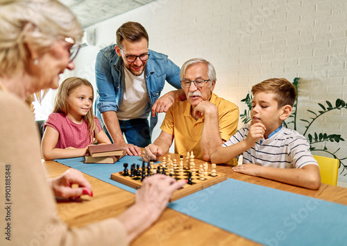 Wallpaper Mural Portrait of a three generation family, grandparents, parents and children playing chess and having fun at home Torontodigital.ca